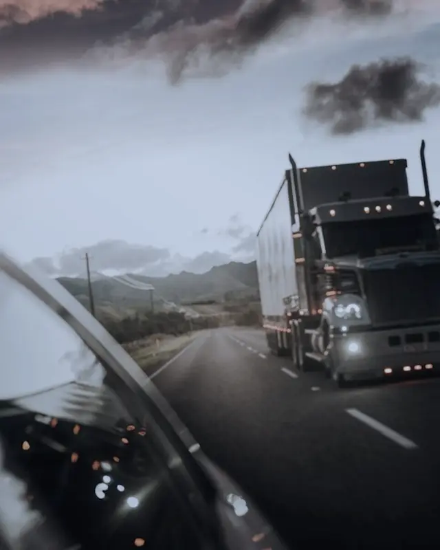 A truck driving on a mountain road at dusk